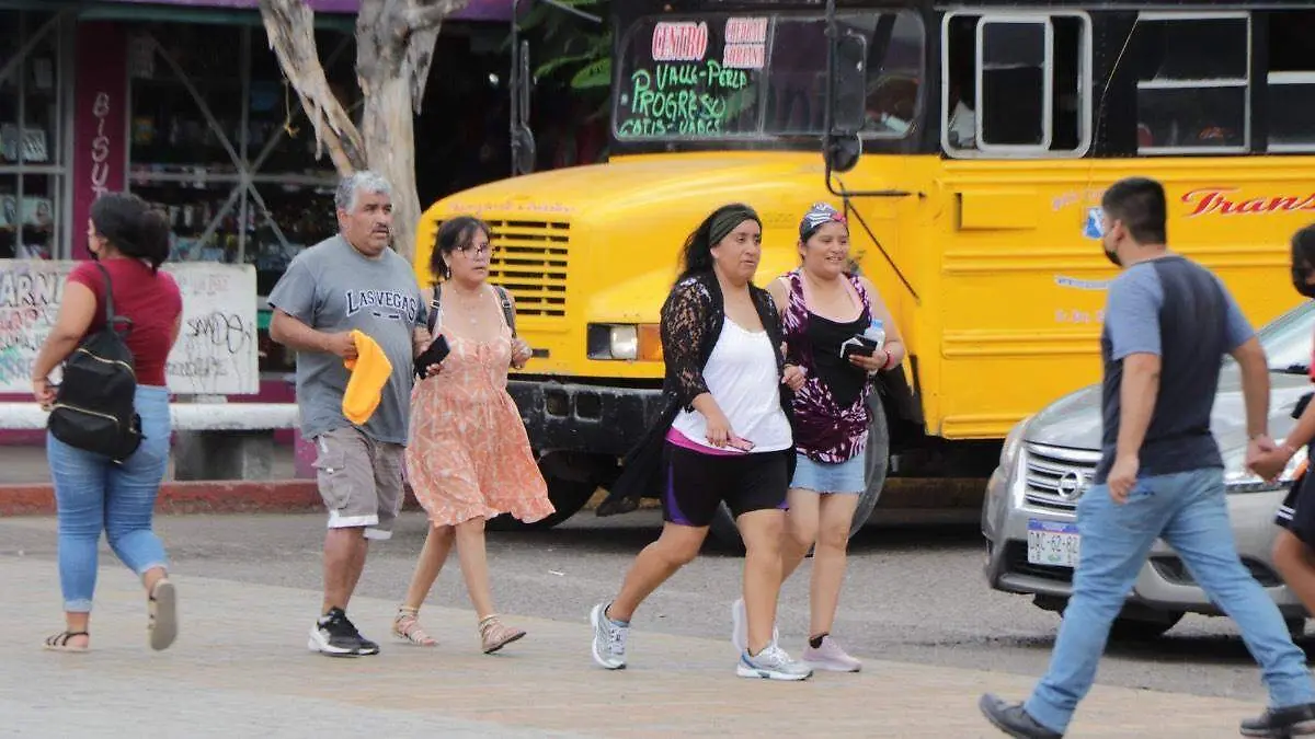 Gente La Paz camiando entre calles y camiones de transporte publico