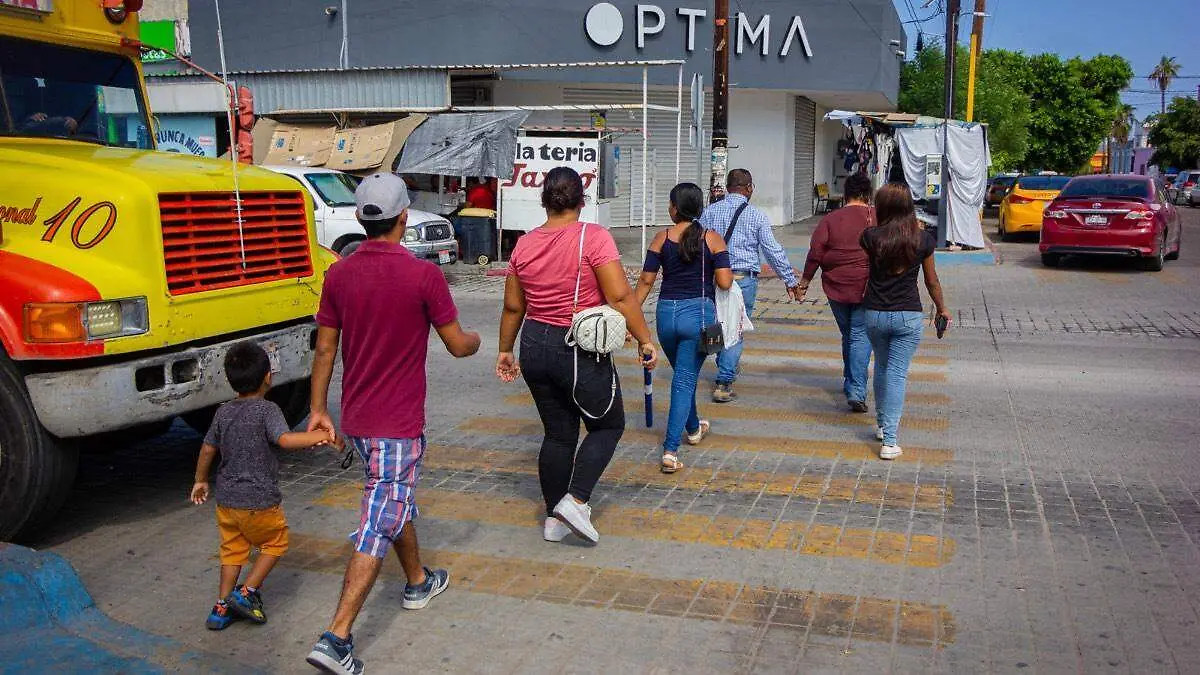 Personas caminando en calles y entre camiones de transporte publico en la paz