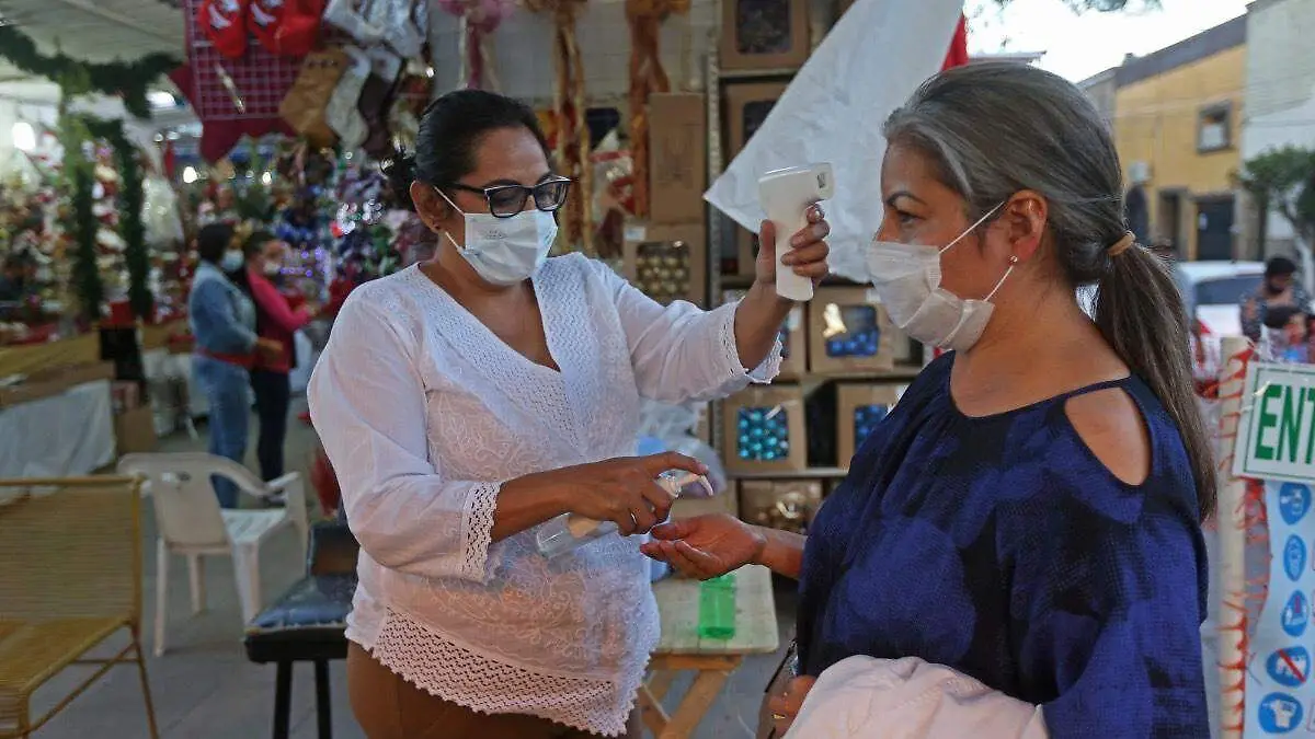 persona-poniendo-gel-antibacterial-mujer-entrando-tianguis-navideño