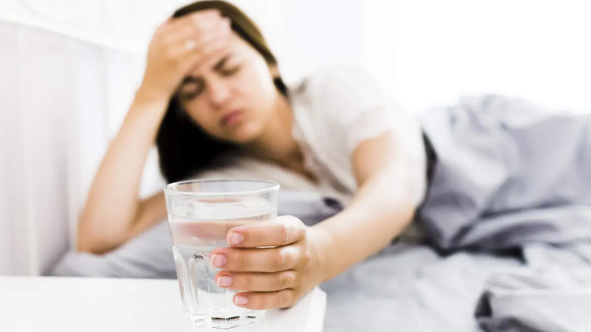 woman-with-headache-taking-glass-water