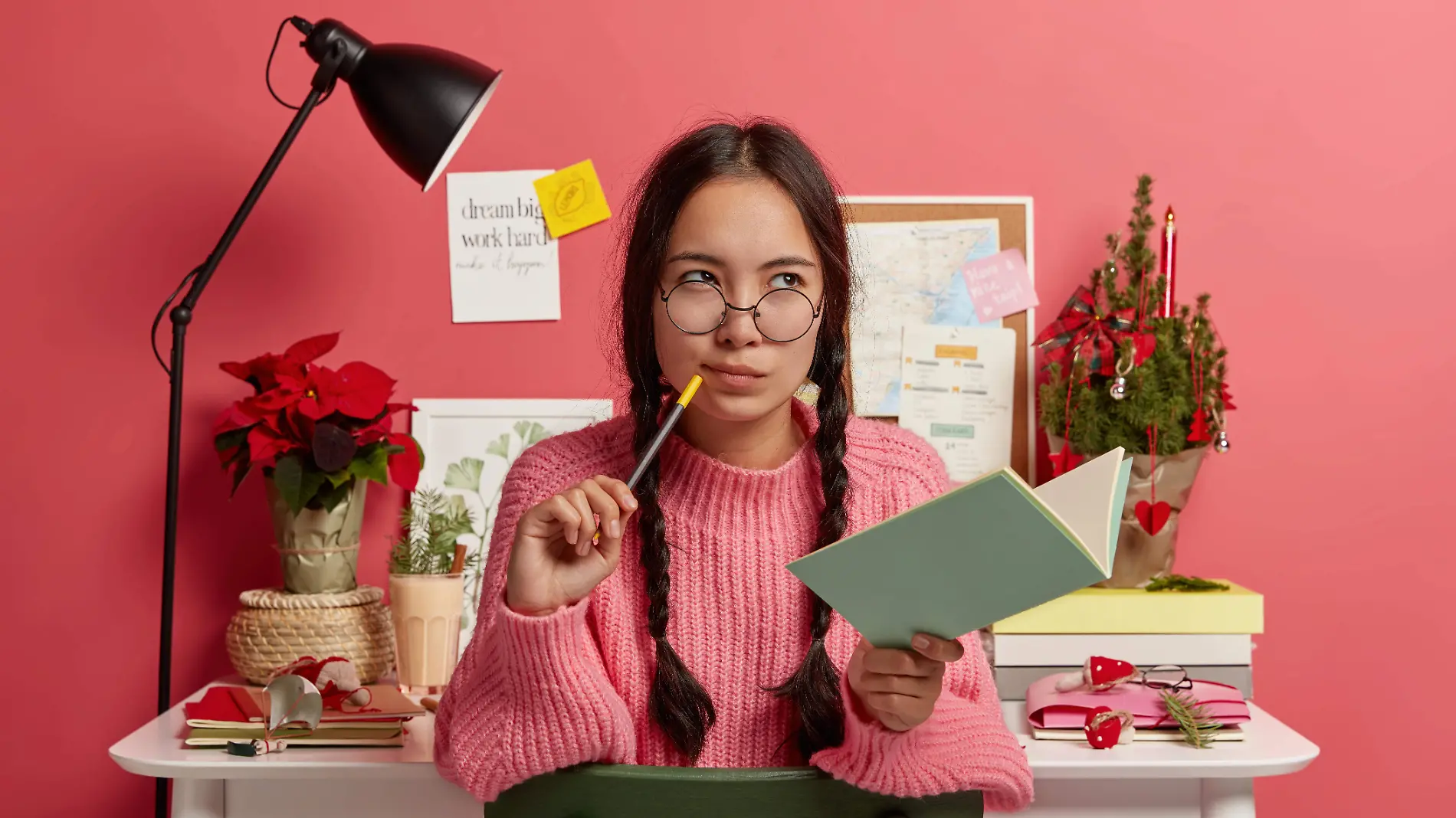 serious-contemplating-asian-girl-with-combed-plaits-holds-notebook-and-pencil-writes-down-future-plans-and-goals-for-coming-christmas