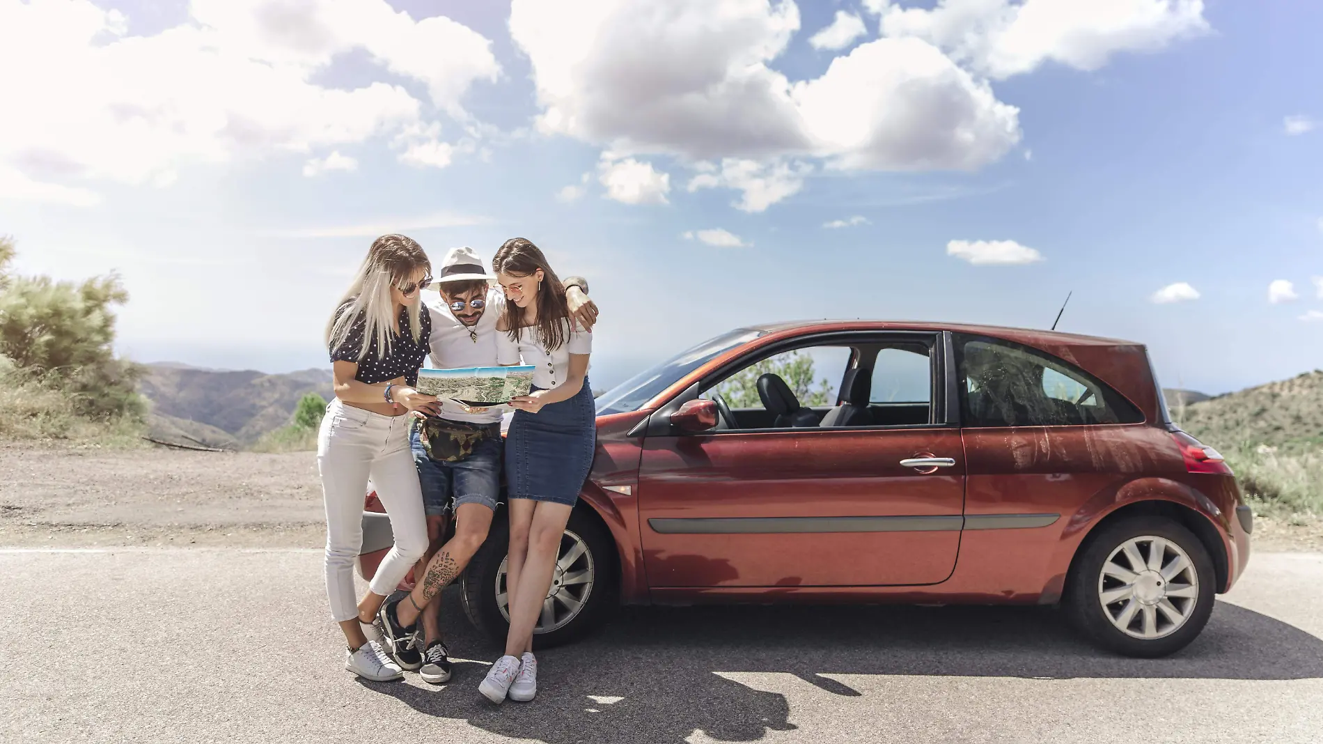 tres-amigos-que-miran-mapa-que-coloca-cerca-coche-moderno-camino