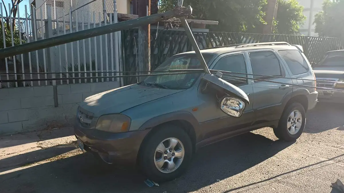 Automóvil sufre daños tras caída de poste
