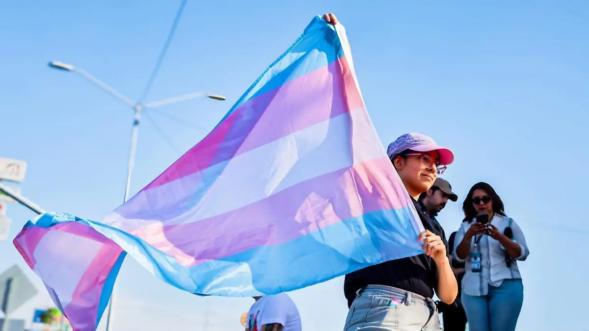 Una persona sostiene con orgullo la bandera trans durante la marcha contra la diversifobia en Mexicali