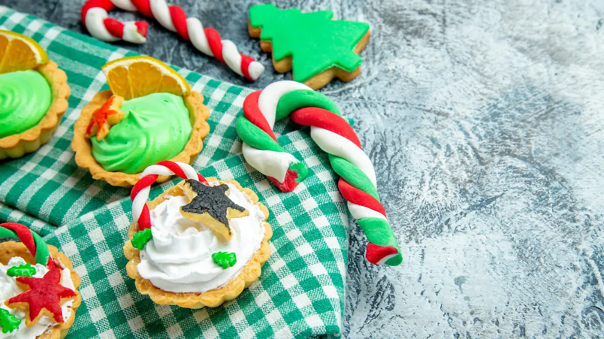 vista-inferior-de-las-pequenas-tartas-de-navidad-en-el-mantel-de-dulces-de-navidad-en-el-espacio-libre-de-la-mesa-gris