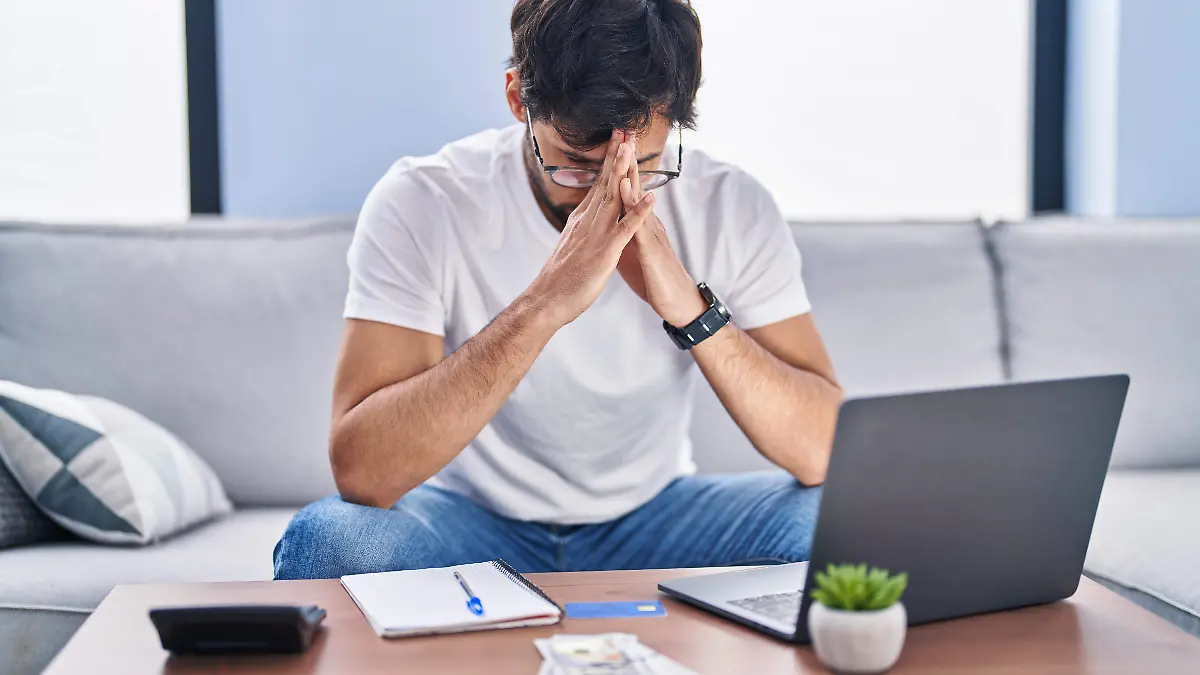 young-hispanic-man-stressed-using-laptop-working-home